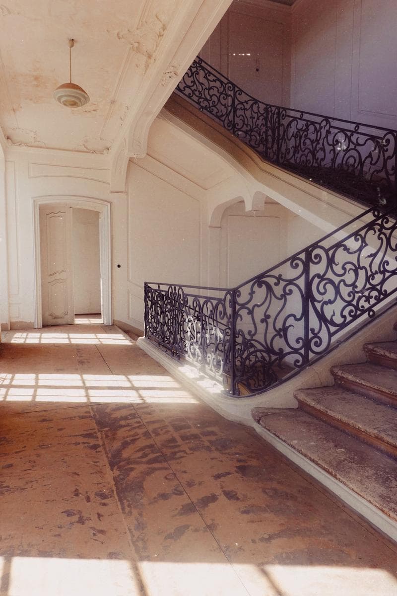 Wrought-iron staircase with sunlight on stone floors