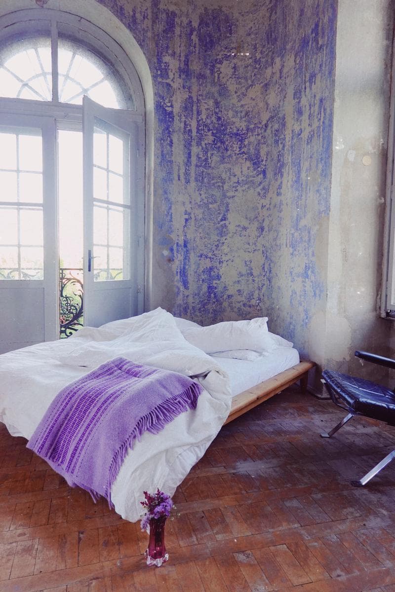 Castle bedroom with arched window and weathered blue walls